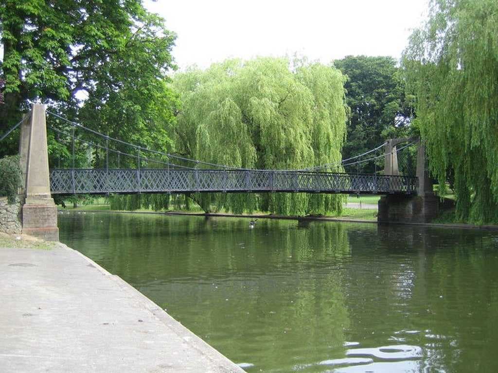 A pedestrian suspension bridge spans the River Lea in Wardown Park.