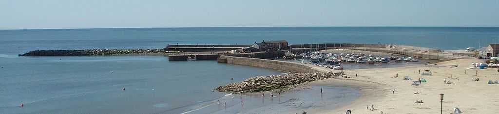 The Cobb, with boats grounded in the harbour at low tide