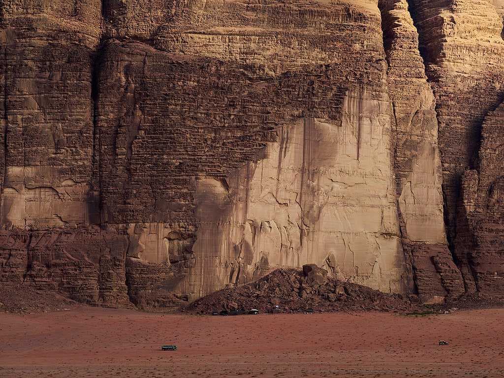 Rock formation at Wadi Rum; black truck below visible for scale