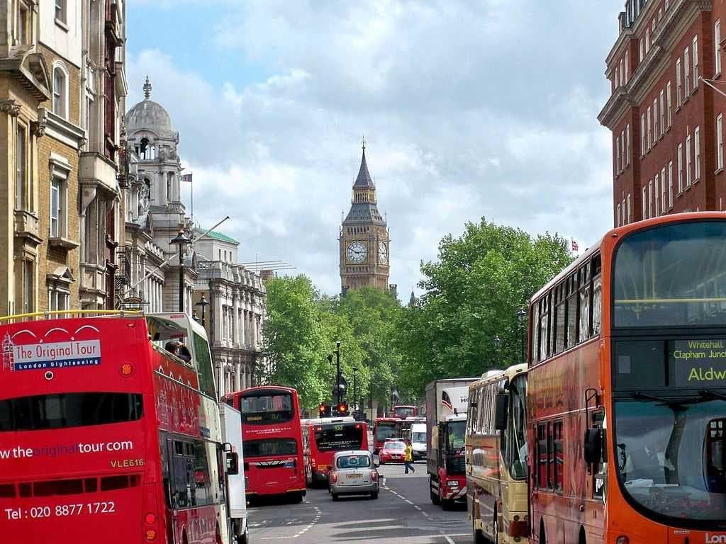Double-decker buses frame a busy Whitehall with Big Ben in the background.