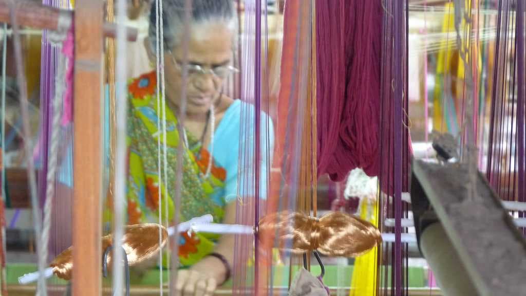 A lady is weaving a cotton saree.